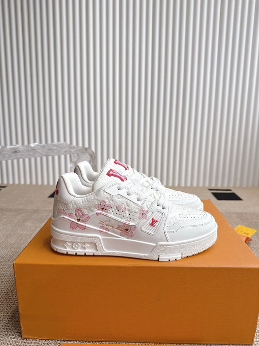 White sneakers with pink floral patterns on an orange box against a white background
